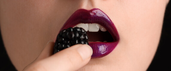 Woman with beautiful lips makeup and blackberry on black background, closeup