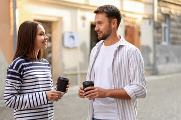 Coffee to go. Couple with paper cups of drinks walking on city street