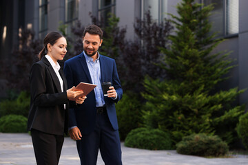 Coffee to go. Man with paper cup of drink and his business partner during meeting outdoors, space for text