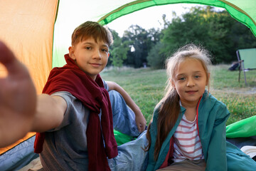 Brother and sister taking selfie in camping tent outdoors