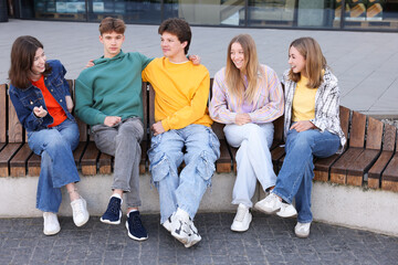 Obraz premium Group of teenagers sitting on bench outdoors