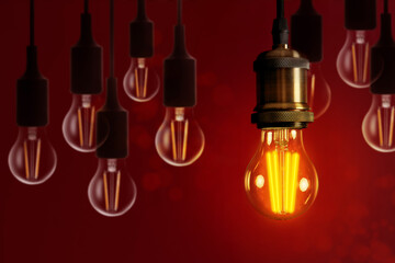 Concept of idea. One glowing light bulb among others against red background