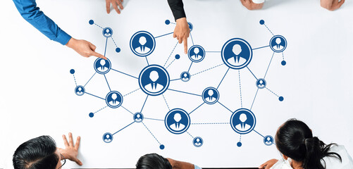 A diverse group of professionals gathers around a table, discussing networking strategies illustrated by interconnected people icons and digital connections. Amity