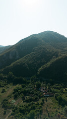 Drone view of Jerma Canyon in Serbia with forested hills and scattered houses. Scenic Balkan mountain landscape under clear blue sky