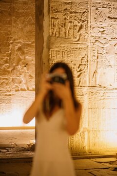 Mujer fotografiando templos egipcios con jerogl&iacute;ficos antiguos iluminados