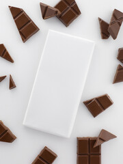 White chocolate bar packaging with space for text or logo insertion surrounded by chocolate pieces top view on a white background close-up promotional photo