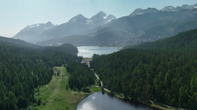 Aerial drone view of Lake Lej da Staz (Mej de Staz) surrounded by pine forest and mountains near St. Moritz in Engadin, Switzerland. Scenic alpine landscape with lakes, forests, and peaks. Perfect for