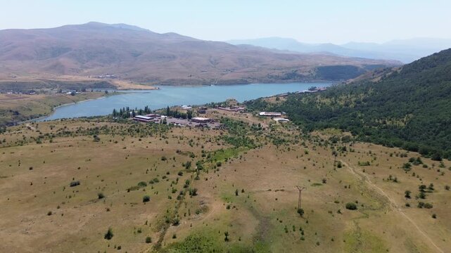 Aerial video of a mountain lake with yellow grasslands around it in Armenia.