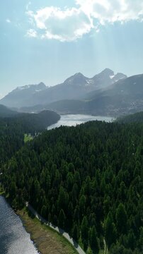 Aerial drone view of Lake Lej da Staz (Mej de Staz) surrounded by pine forest and mountains near St. Moritz in Engadin, Switzerland. Scenic alpine landscape with lakes, forests, and peaks. Perfect for