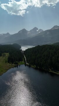 Aerial drone view of Lake Lej da Staz (Mej de Staz) surrounded by pine forest and mountains near St. Moritz in Engadin, Switzerland. Scenic alpine landscape with lakes, forests, and peaks. Perfect for