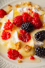 Grilled brie cheese with berries and honey. Dessert with natural ingredients.