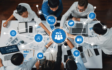 Diverse team members gather around a table using digital tools and visual aids to brainstorm and strategize for effective communication and media practices. Amity