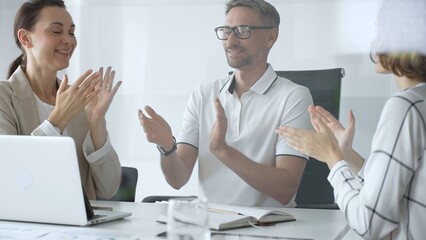 Professional team applauding, celebrating collaborative success and recognizing outstanding performance during corporate meeting in office. Business people concept