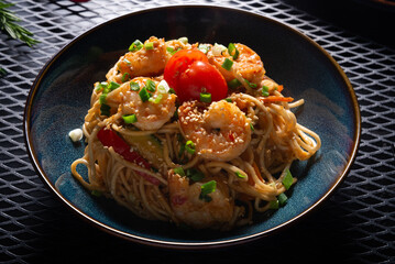 Noodles with Shrimp and Vegetables on Dark Plate on Black Table, Top View