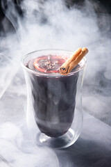 Hot Mulled Wine with Orange Slice and Cinnamon Stick in Glass on Dark Table with Steam