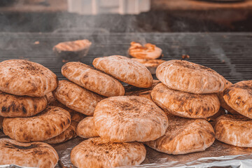 Freshly baked flatbreads stacked in piles on a grill, golden brown and rustic with smoky char marks. Concept of flatbread preparation and traditional street food flavor