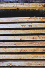 Closeup showing wooden beehive frames stacked in rows with visible honeycomb residue and several bees crawling on surfaces, highlighting beekeeping equipment and insect activity