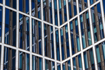 Modern architectural design featuring a striking glass facade with geometric patterns, reflecting sunlight and creating an intriguing visual experience in urban environments