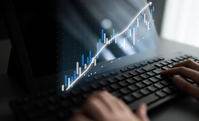 A close-up view of hands typing on a keyboard while interacting with financial data displayed on a...