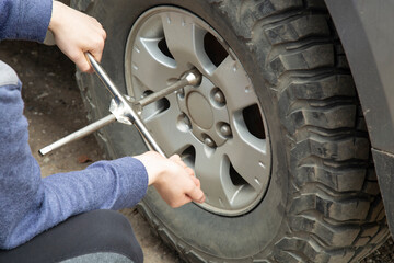 A man removes a wheel from a car using a wrench.
