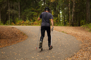 Fototapeta premium A man roller-skating in an autumn park. Cross-country.