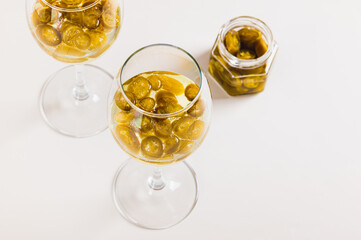 Green jalapeno pepper pieces in white wine in glasses on table
