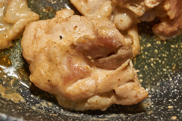 Pieces of chicken meat are fried in a frying pan, exuding flavor and mouth-watering appearance. Delicious chicken pieces are fried in a frying pan until golden brown.