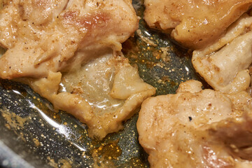 Pieces of chicken meat are fried in a frying pan, exuding flavor and mouth-watering appearance. Delicious chicken pieces are fried in a frying pan until golden brown.