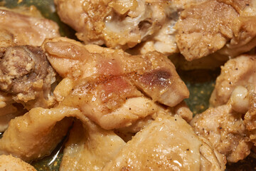 Pieces of chicken meat are fried in a frying pan, exuding flavor and mouth-watering appearance. Delicious chicken pieces are fried in a frying pan until golden brown.