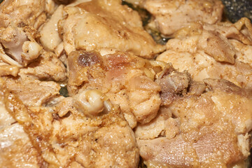 Pieces of chicken meat are fried in a frying pan, exuding flavor and mouth-watering appearance. Delicious chicken pieces are fried in a frying pan until golden brown.