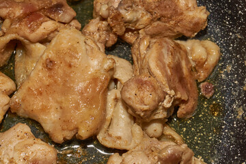Pieces of chicken meat are fried in a frying pan, exuding flavor and mouth-watering appearance. Delicious chicken pieces are fried in a frying pan until golden brown.