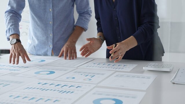 Professional team analyzing financial reports, sharing insights and planning strategic decisions in modern workplace setting. Business people concept