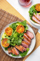 A plate of meat and salad with a glass of wine