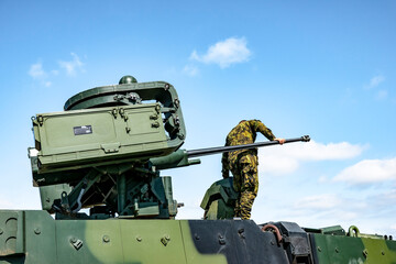 A turret with a 30mm cannon on an armored vehicle on which there is a soldier
