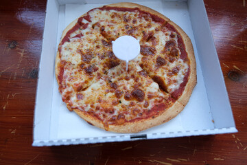 Take away pizza in a white box on a wooden table. Close-up.