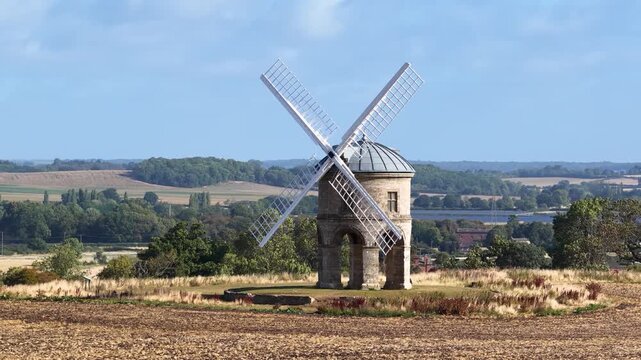 Aerial drone footage circling from right to left: A windmill in the English countryside during summer in daylight. Superzoom compression in background. Isolated subject. Chesterton