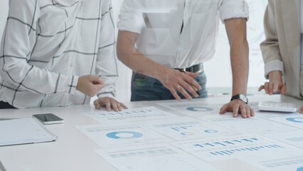 Professional team reviewing financial charts, working together in contemporary workspace, brainstorming strategic improvements. Business people concept