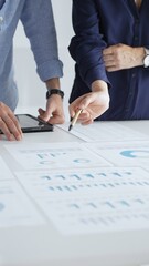 Professional team reviewing financial documents, pointing at charts on desk, collaborating to analyze data and strategize business growth. Business people concept