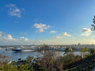 Large cruise ship docked in Havana Harbor, Cuba. City skyline and Capitol building in warm sunset light