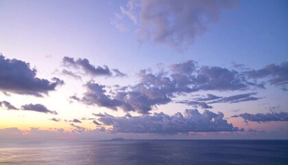 Obraz premium Serene seascape at dusk, with calm water, a vibrant sky filled with clouds, and a distant silhouette