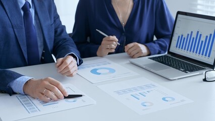 Businesspeople colleagues are reviewing financial data, analyzing charts and graphs, pointing at laptop screen during corporate meeting. Business people and finance concept
