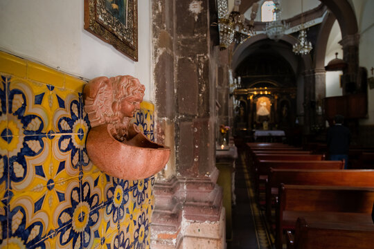 Interior of Templo Nuestra Se&ntilde;ora de la Salud with holy water font, ceramic tiles, and illuminated altar