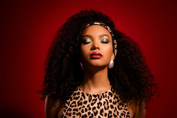 Fototapeta premium Stunning young woman posing with glamorous makeup, leopard print outfit, and bold curly hair
