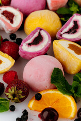 Colorful mochi ice cream with fresh fruits and berries on white background, close up