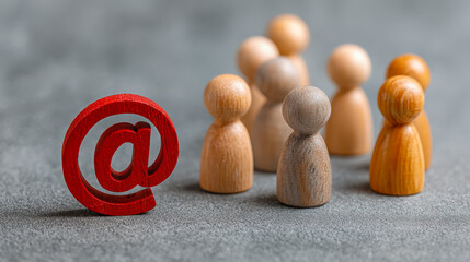 Wooden figures gathering around a red '@' symbol, symbolizing online community and digital communication