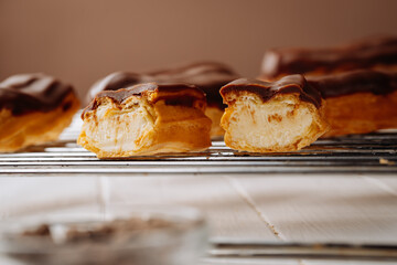 Close up of halved chocolate eclairs with creamy filling on a cooling rack