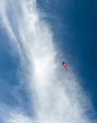 American Flag Kite Flying High Against Dramatic Blue Sky with White Wispy Clouds at Kite Festival