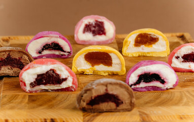 Assorted colorful mochi ice cream halves on wooden board, close-up view, studio lighting