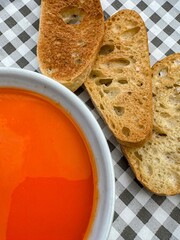 Bowl of tomato soup with toast on checked cloth