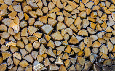 A Close-up view of Neatly stacked Firewood Logs, showcasing the natural texture and patterns of the wood. The Logs are cut into various shapes and sizes.